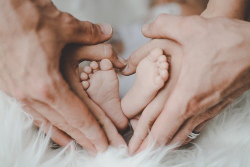 Des petits pieds qui viennent de naître sont entourés des mains de ses parents