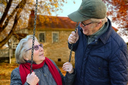 Un couple de personnes âgées rigolent ensemble sur une balançoire